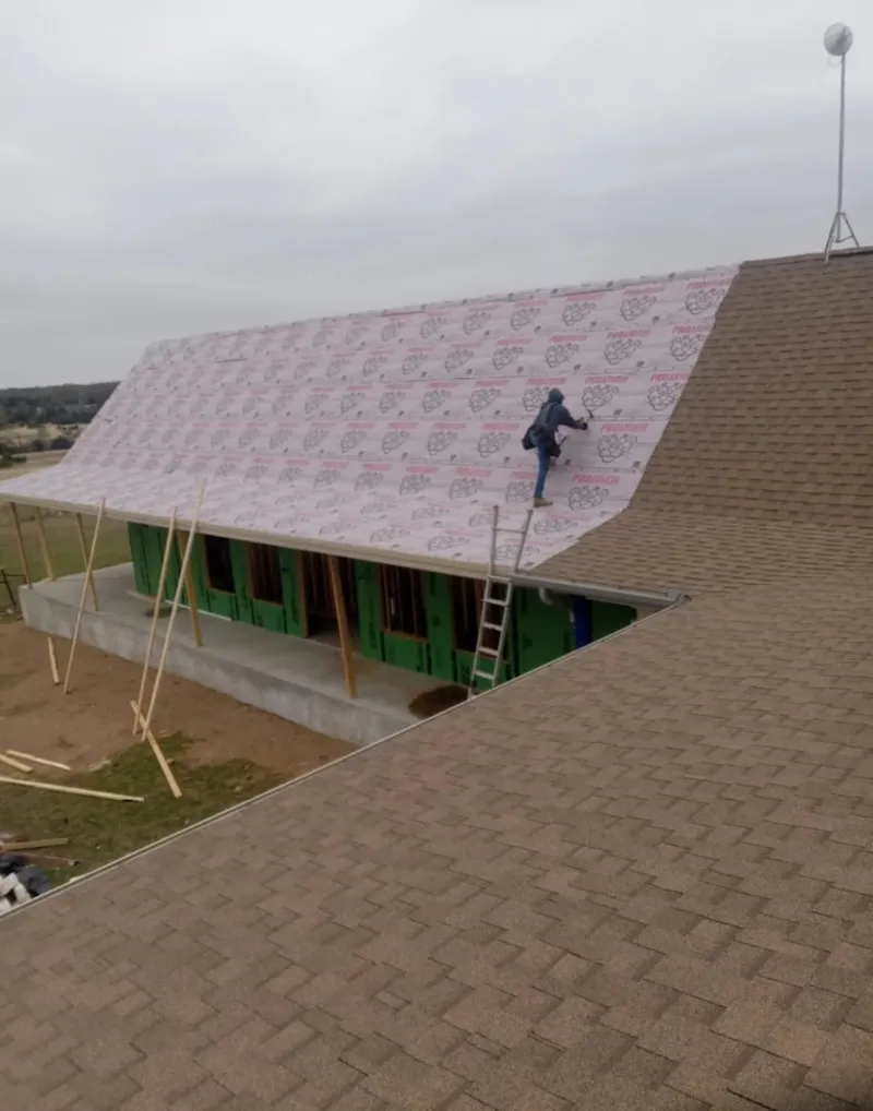 Worker preparing underlayment for a metal roof installation in Great Falls